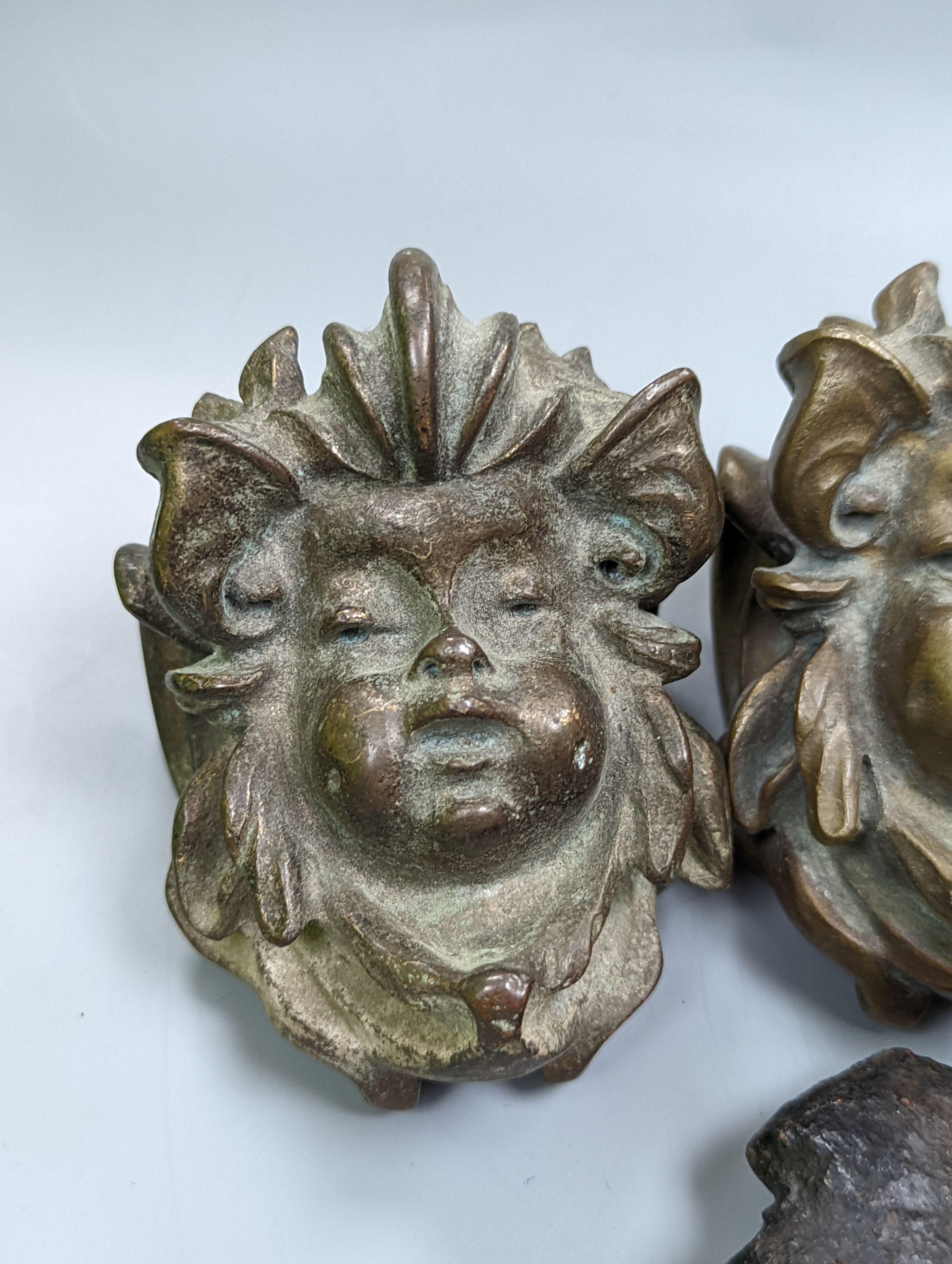 A set of three cast bronze mask-form furniture mounts, 9cm. high